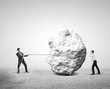 two businessman pulling a rope rock