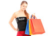 A young smiling female holding shopping bags and posing