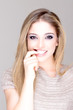 Portrait of a cute blond girl biting her nail
