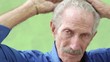Elderly hispanic man smiling at camera, brushing hair with comb
