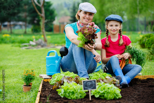 Photo: Gardening - mother and daughter working in vegetable garden Gardening - mother and daughter working in vegetable garden