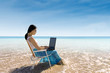 Attractive woman typing on laptop at beach