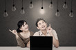 Photo: Couple with laptop looking at lit bulb Couple with laptop looking at lit bulb