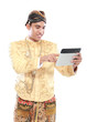 man with traditional java suit using tablet PC
