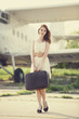 Lonely girl with suitcase at near airplane.