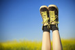 vintage sneakers resting on blue sky and rapseed field backgroun