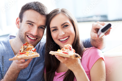 Photo: Couple with pizza and TV remote Couple with pizza and TV remote