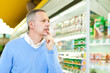 Foto: Man comparing products at the supermarket Man comparing products at the supermarket