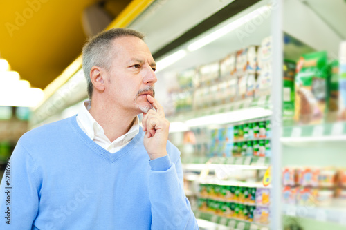 Photo: Man comparing products at the supermarket Man comparing products at the supermarket