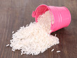 Overturned bucket with grains on wooden background