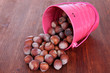 Overturned bucket with hazelnuts on wooden background