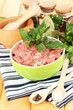 Bowl of raw ground meat with spices on wooden table
