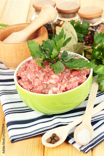Photo: Bowl of raw ground meat with spices on wooden table Bowl of raw ground meat with spices on wooden table