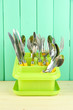 Knives, spoons, forks in plastic container for drying,