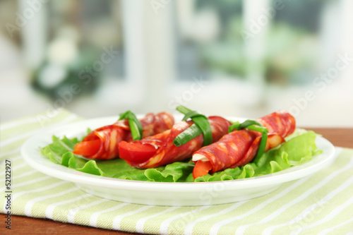 Photo: Salami rolls on white plate on bright background Salami rolls on white plate on bright background