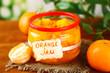 Orange jam with zest and tangerines, on brown wooden table