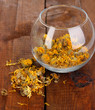 Dried herb in glass container on wooden table close-up