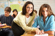 Teacher Helping Female Pupil Studying At Desk In Classroom