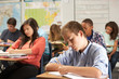 Male Pupil Studying At Desk In Classroom
