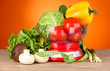 Fresh vegetables in scales on table on orange background