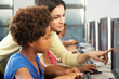 Teacher Helping Elelmentary Students Working At Computers