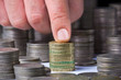 Photo: Closeup of stack of british pound coins with a male hand Closeup of stack of british pound coins with a male hand