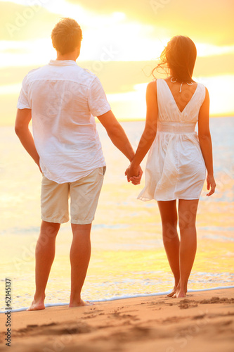 Photo: Young couple holding hands at beach sunset Young couple holding hands at beach sunset