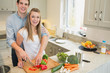 Couple smiling and working in the kitchen
