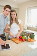 Photo: Woman chopping peppers with man typing on the tablet pc Woman chopping peppers with man typing on the tablet pc