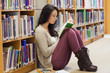 Photo: Student leaning against a shelf in a library Student leaning against a shelf in a library