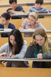Students learning in a lecture hall with one girl using tablet