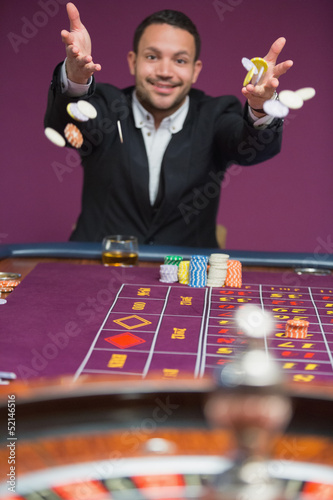Photo: Man throwing chips onto roulette table Man throwing chips onto roulette table