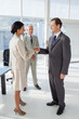 Two people shaking their hands with colleague watching them