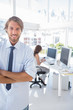 Smiling desginer standing in office with arms crossed