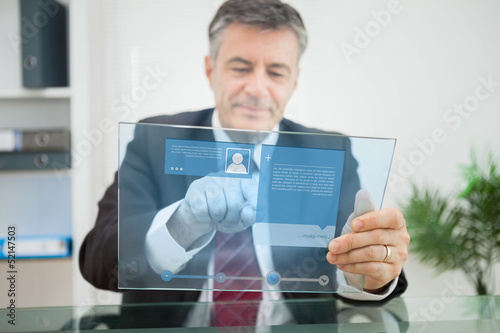 Photo: Businessman using futuristic touchscreen to view social media pr Businessman using futuristic touchscreen to view social media pr