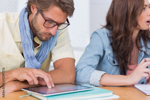 Photo: Editor using tablet at meeting as colleague is talking Editor using tablet at meeting as colleague is talking