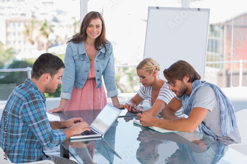 Photo: Team having meeting with one woman smiling at camera Team having meeting with one woman smiling at camera