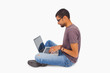 Photo: Man wearing glasses sitting on floor using laptop Man wearing glasses sitting on floor using laptop