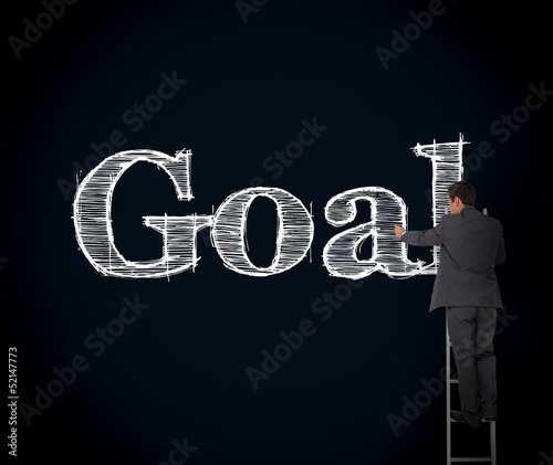 Photo: Businessman writing goal on a giant blackboard Businessman writing goal on a giant blackboard