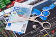 Scissors cutting  euro  banknote, dices cube with the word STOP.