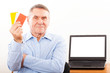 Elderly man smiling and showing credit card
