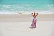 Girl drawing a heart on the sandy beach