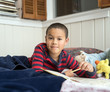 Young Boy Reading in Bed with Workbook