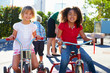 Foto: Two Girls Riding Tricycles In Playground Two Girls Riding Tricycles In Playground