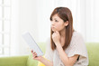 部屋でタブレットを見る女性