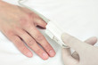 Doctor in a glove puts the sensor on patient's finger. Symbol of
