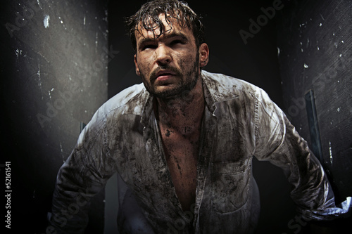 Photo: Dirty man between grunge walls Dirty man between grunge walls