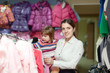 Photo: mother with girl at clothes store. Focus on woman mother with girl at clothes store. Focus on woman