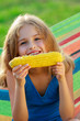 Photo: Child in the garden - lovely girl eating corn on the cob Child in the garden - lovely girl eating corn on the cob