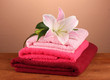 stack of towels with pink lily on a brown background